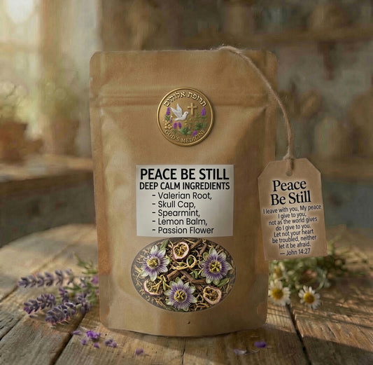 A kraft paper pouch labeled 'PEACE BE STILL' with a hanging tag, photographed on a rustic wooden surface with blurred flowers and a warm indoor background. The pouch shows printed ingredient names and a circular brand seal reading 'The Calm Sanctuary.

