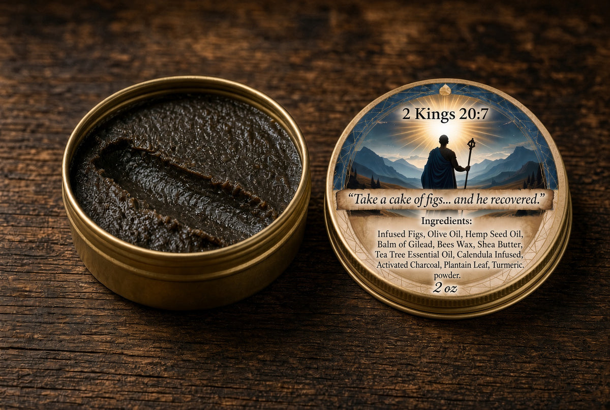 An open round brass tin showing a dark brown paste or balm inside, with the lid placed beside it on a wooden surface. The lid has a printed label with a mountain-and-sun illustration and text including '2 Kings 20:7' and a product description.

